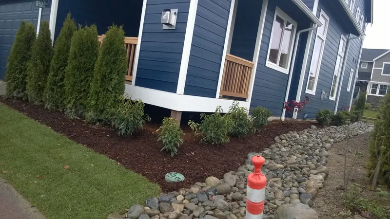 Foundation plantings and fresh beds along a blue craftsman home