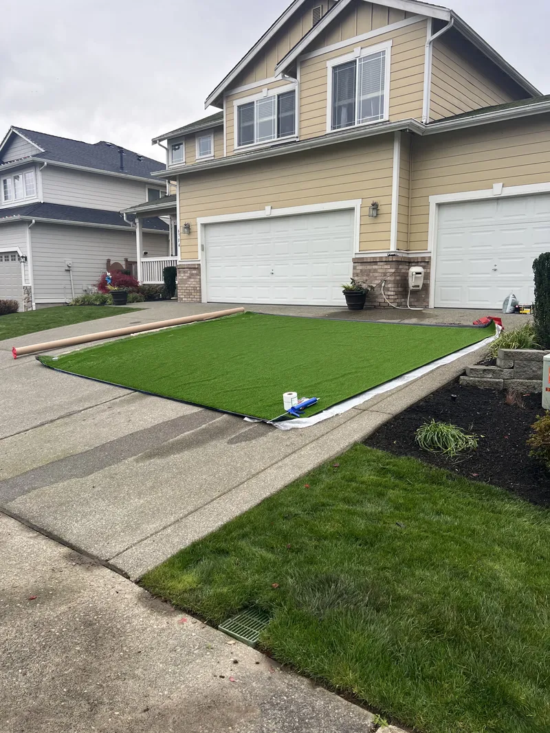 New synthetic turf installed in a clean strip along a residential driveway